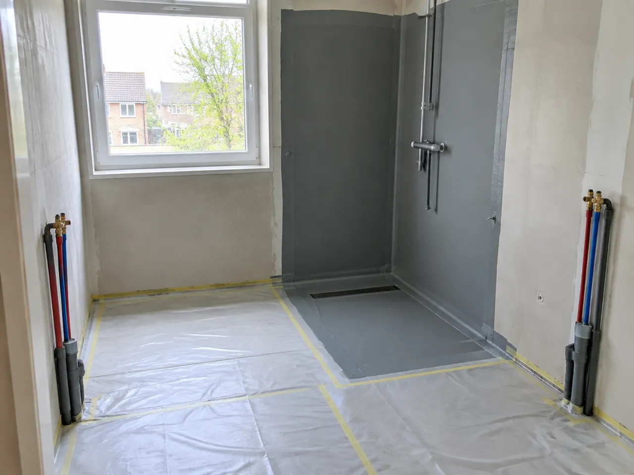 Sfeerbeeld: badkamer in aanbouw met waterdichte laag in de douchehoek en nieuwe leidingen